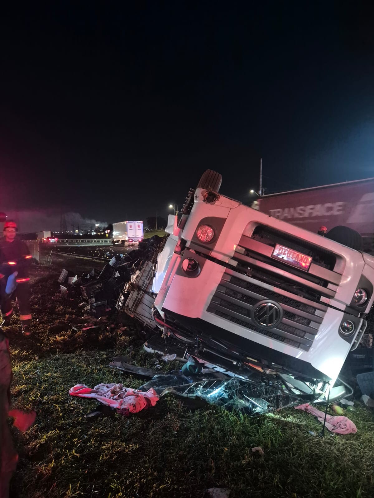 Motorista de carreta fica ferido após capotamento com carga de mangas na Anhanguera