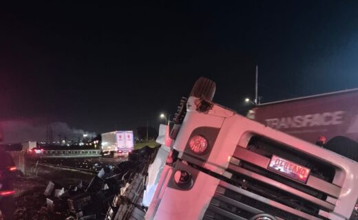 Motorista de carreta fica ferido após capotamento com carga de mangas na Anhanguera