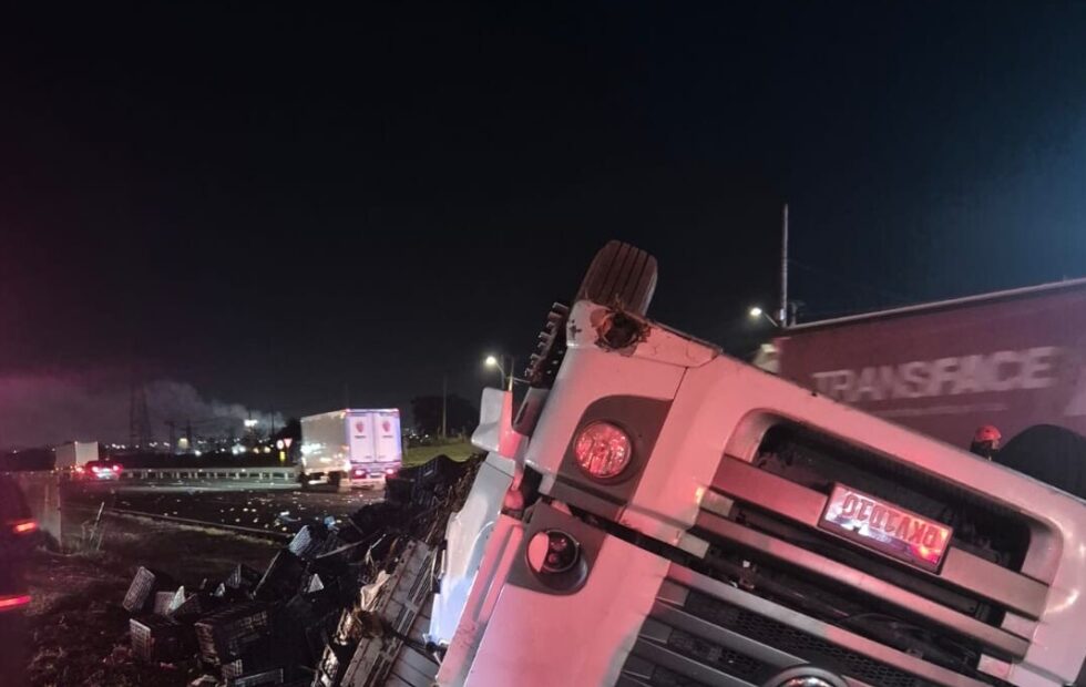 Motorista de carreta fica ferido após capotamento com carga de mangas na Anhanguera